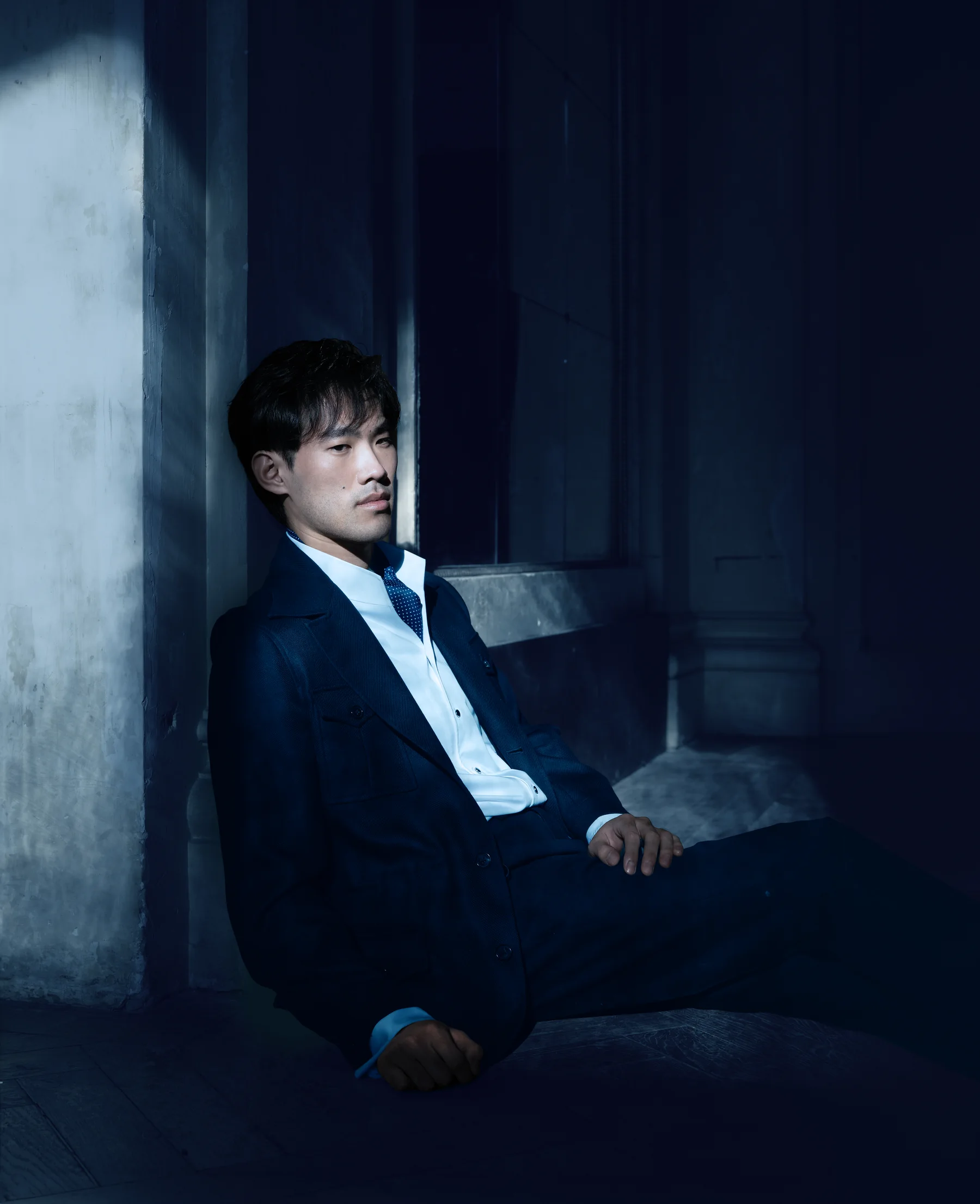 Bruce Liu seated against a blue wall