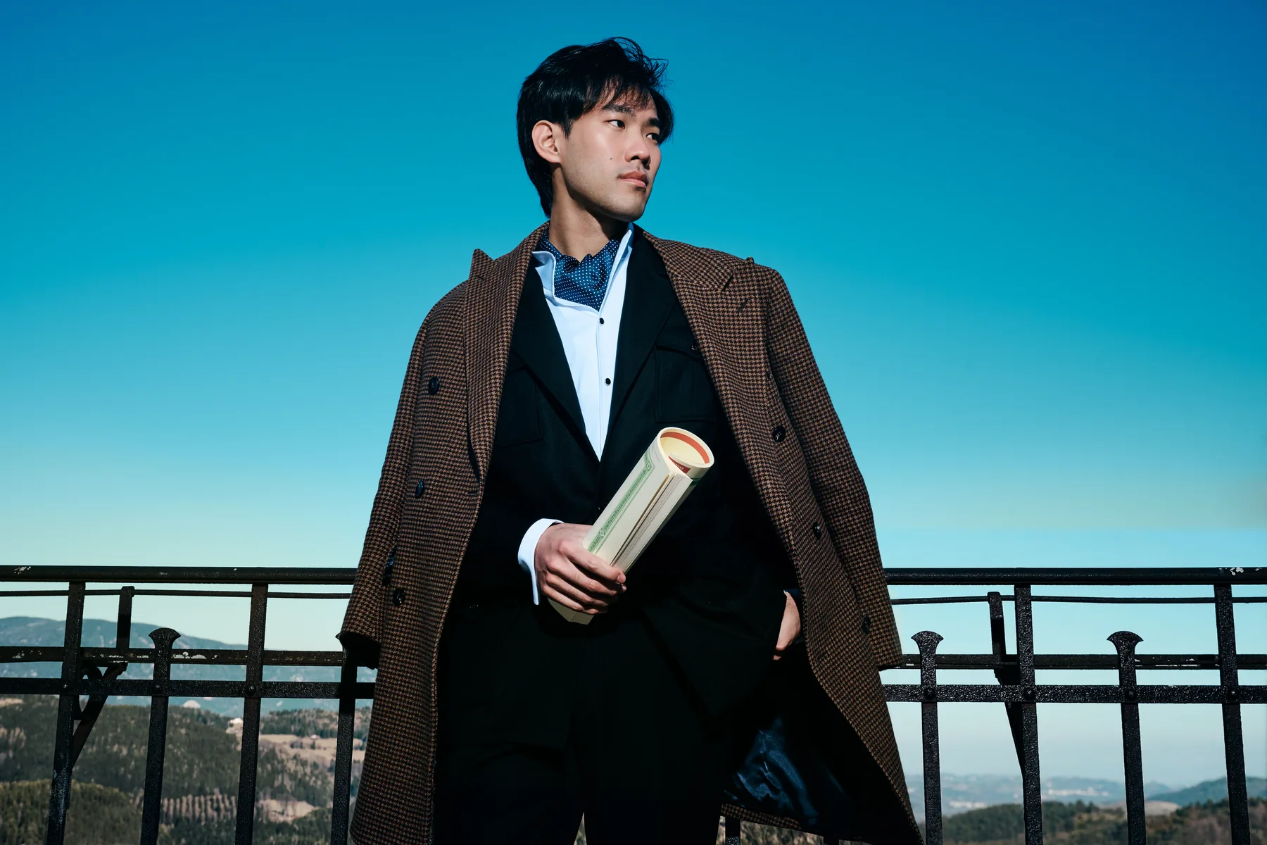 Bruce Liu standing on a promenade in a brown overcoat